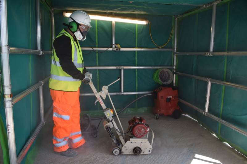 Carousel 1 - A site operative working on a floor maintenance project inside a dust enclosure_