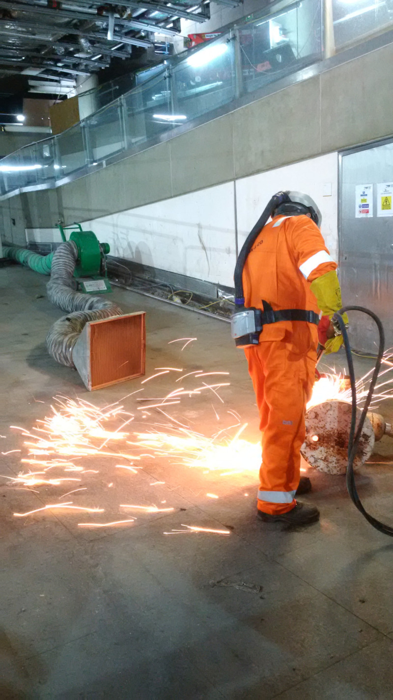 Carousel 1 - Worker creating burning fume at a project inside Waterloo train station in London with the fume being captured at the source