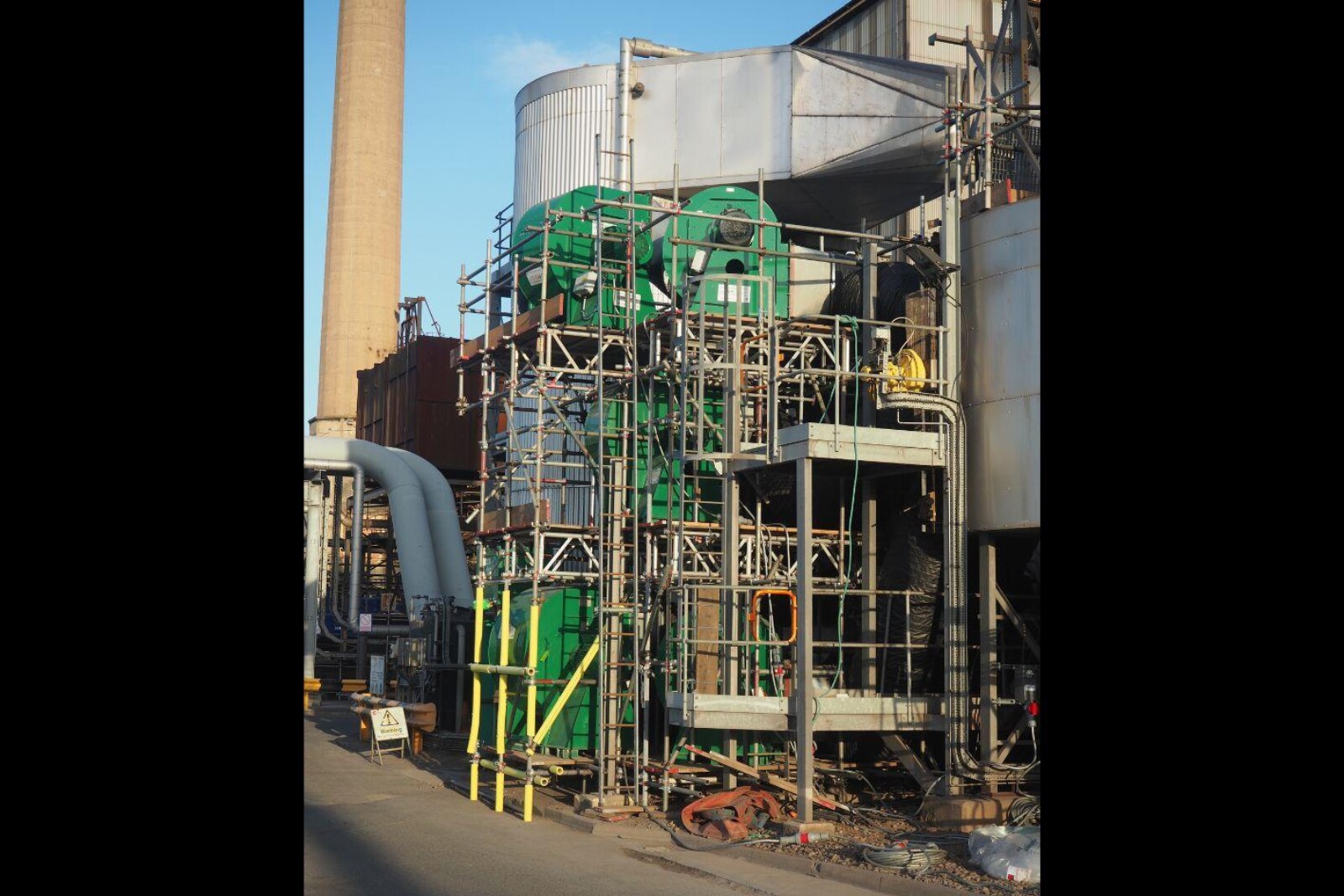 4 VENTEX Centrifugal Fan 800S units on the bottom, middle and top level of a scaffolding structure next to an industrial plant_