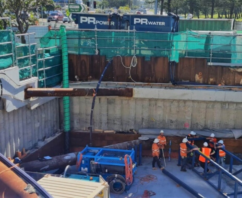 Crew working in an excavation with green ventilation ducting and site generators