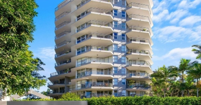 Apartment tower with balconies surrounded by palm trees