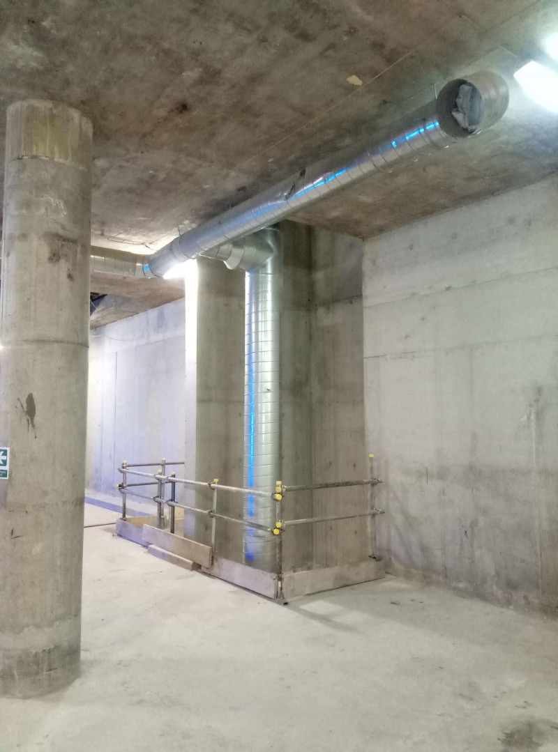 Galvanised ventilation ducting fixed to concrete columns in a basement