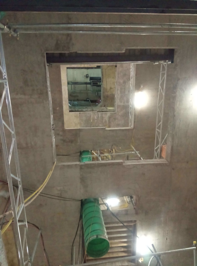 Looking up a concrete shaft with green ducting and access scaffolding