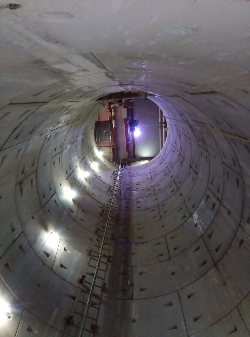 Inside a concrete lined tunnel with lighting and a track