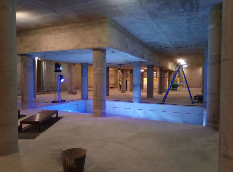 Large concrete basement space with columns and blue lighting