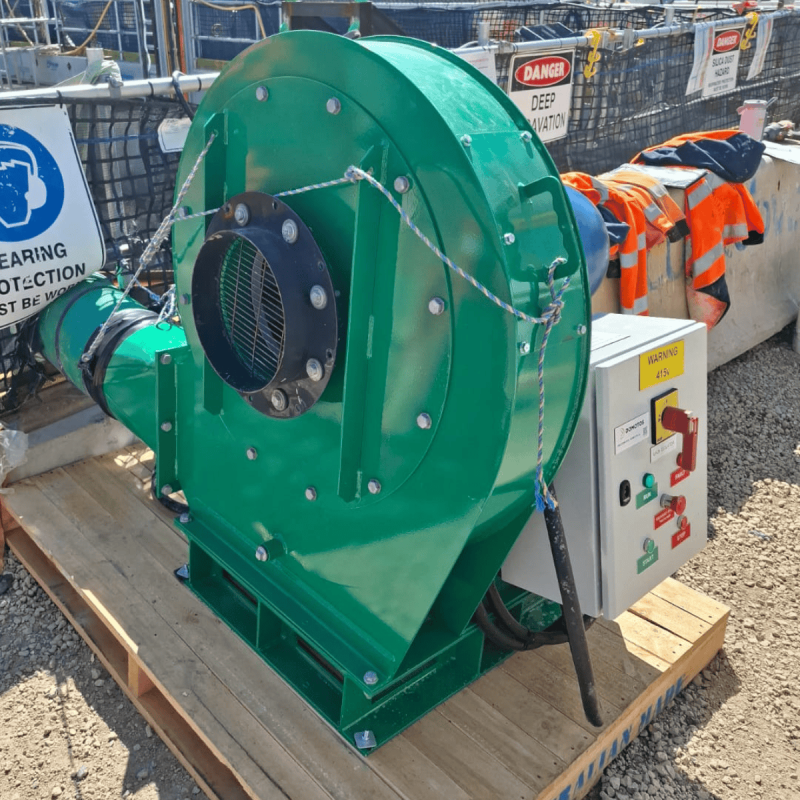 Green RVT centrifugal fan with control panel on a pallet beside a deep excavation