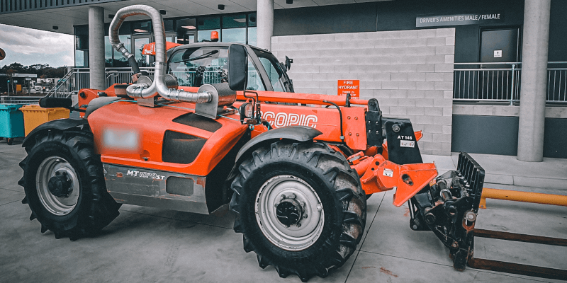 Telehandler fitted with an exhaust filtration system outside a warehouse