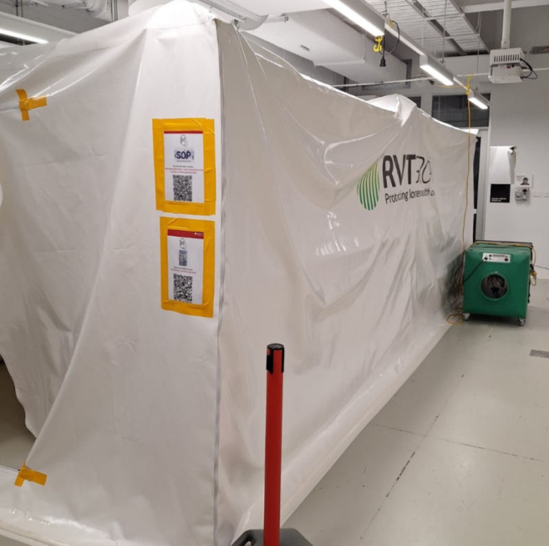 White RVT dust containment enclosure with safe work signage inside a building