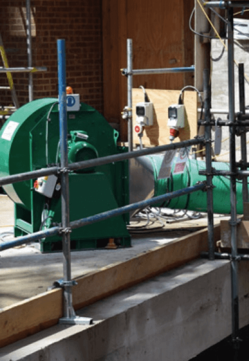 Green RVT fan and ducting set up beside scaffolding on a building