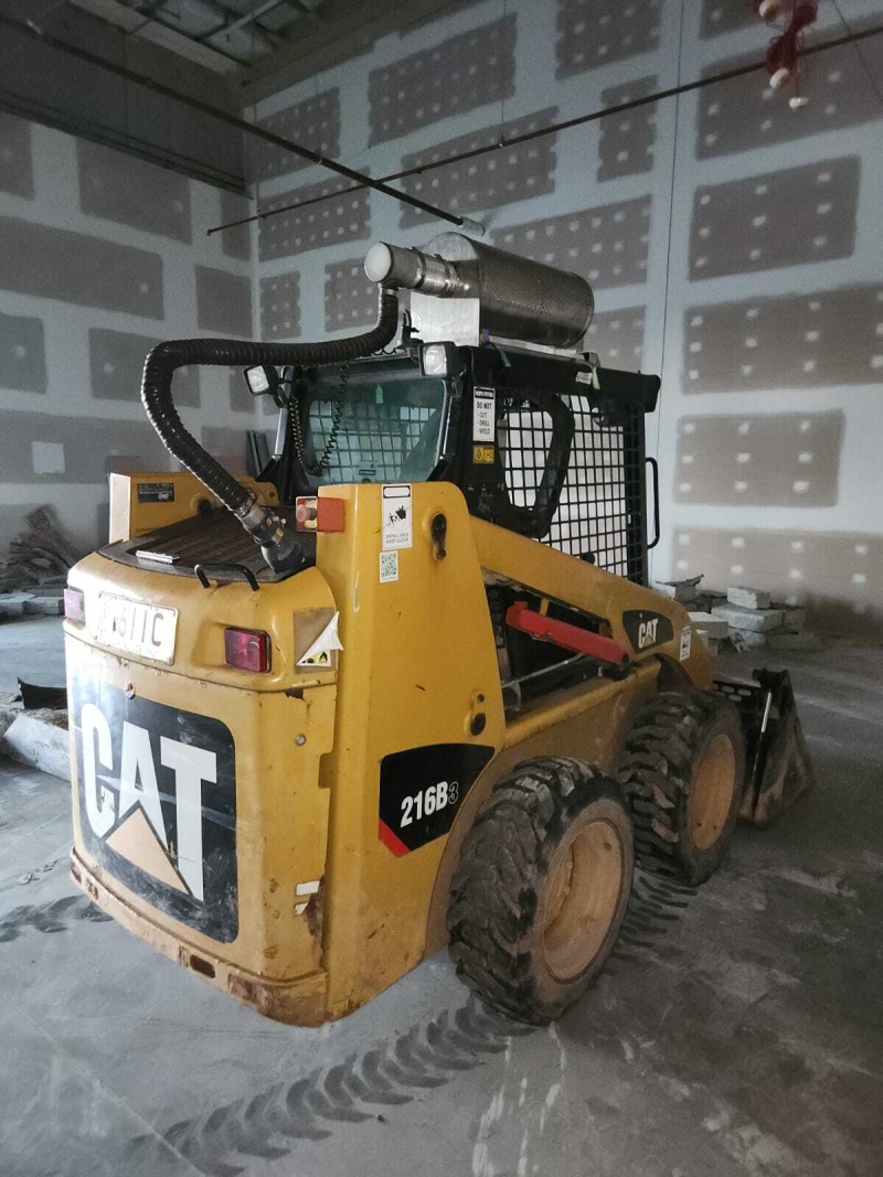 CAT 216B skid steer loader parked inside a building under fit out