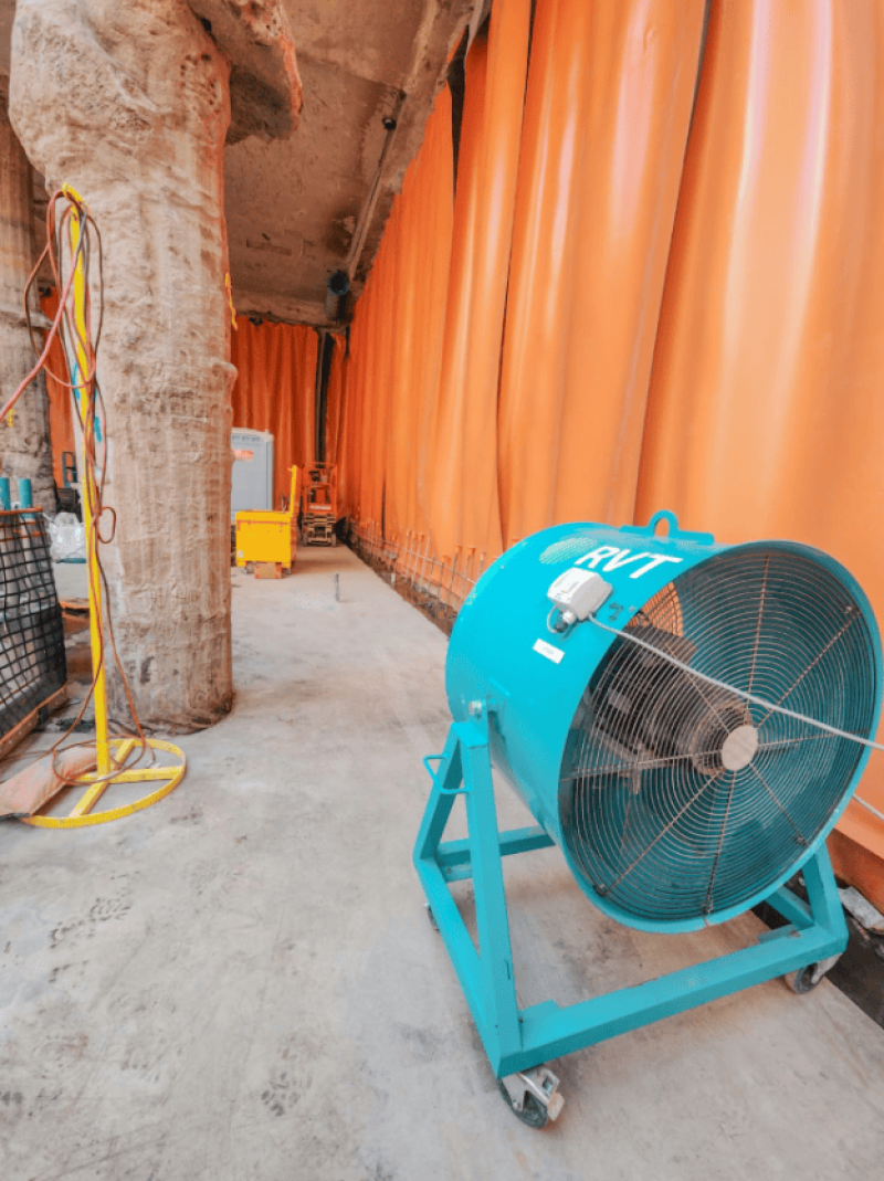 Blue RVT mobile ventilation fan on a basement strip out site with orange sheeting