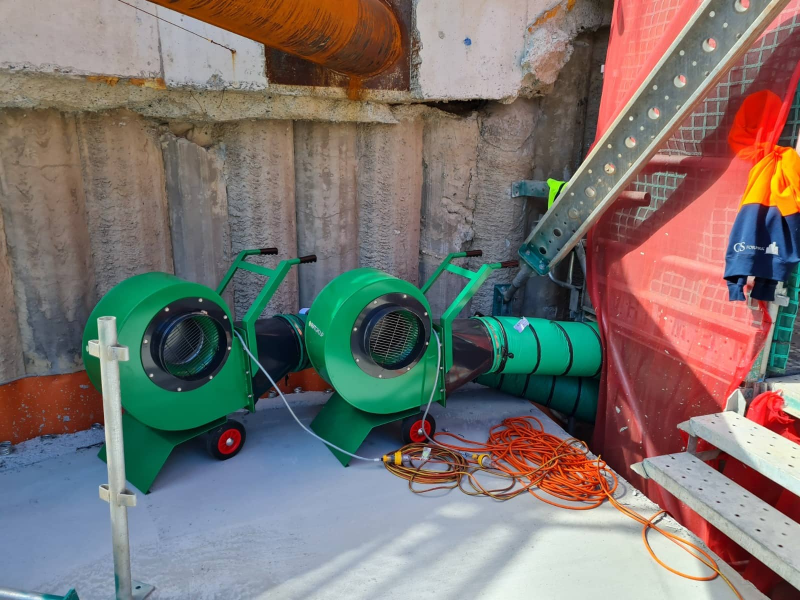 Two green RVT ventilation fans with ducting at the base of an excavation