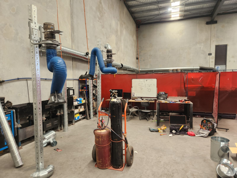Welding fume extraction arms above work benches in a fabrication workshop