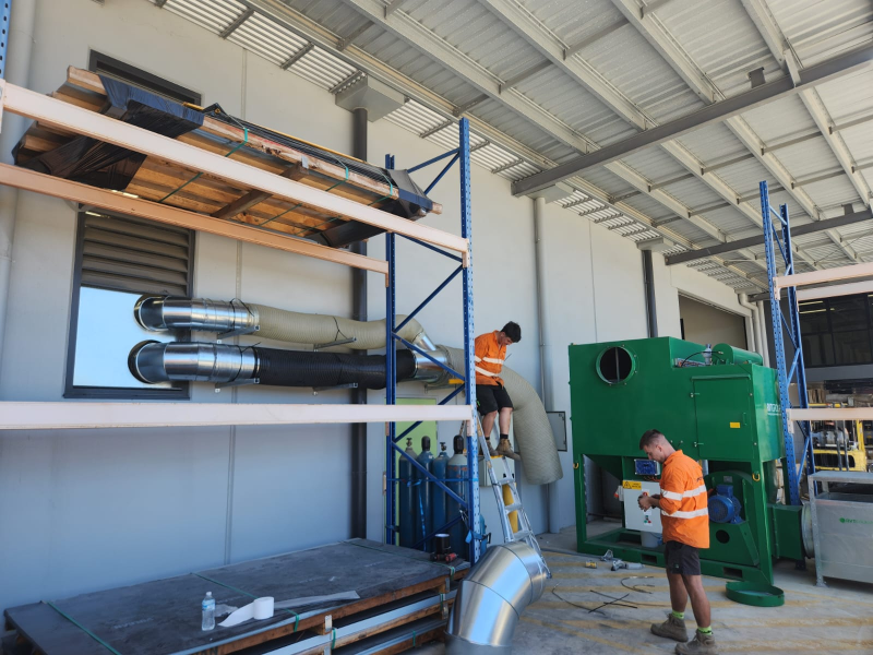Warehouse team loading ventilation ducting and a green RVT unit onto racking