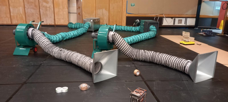 Two RVT extraction fans with ducting and hoods on a hall floor