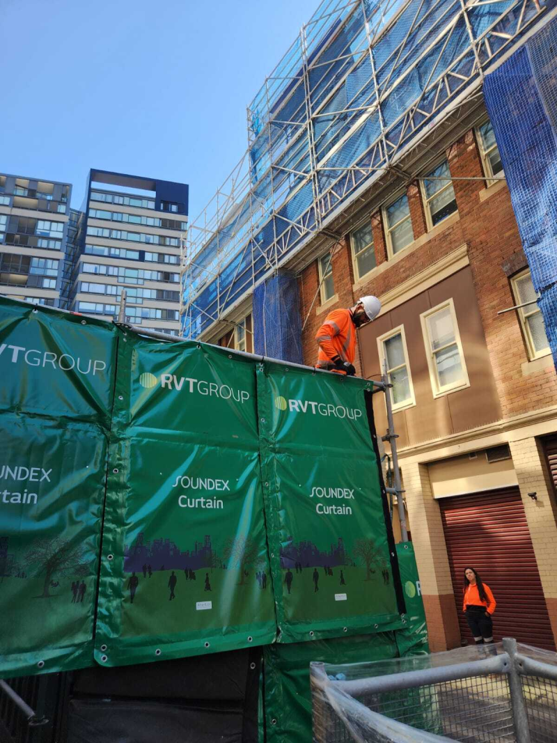 Worker installing RVT SOUNDEX Curtain acoustic screens on scaffolding