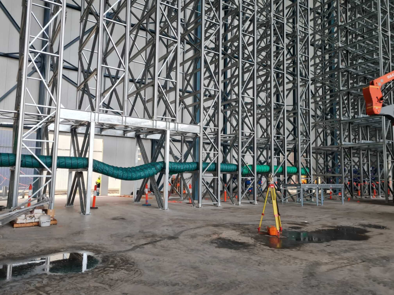 Green ventilation ducting running through a warehouse with high bay racking