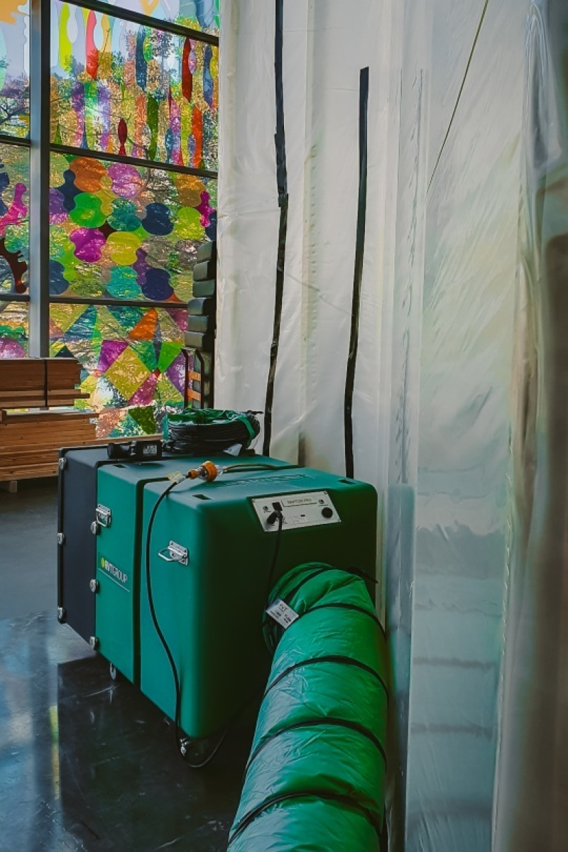 RVT filtration unit and green ducting inside a gallery beside a stained glass window